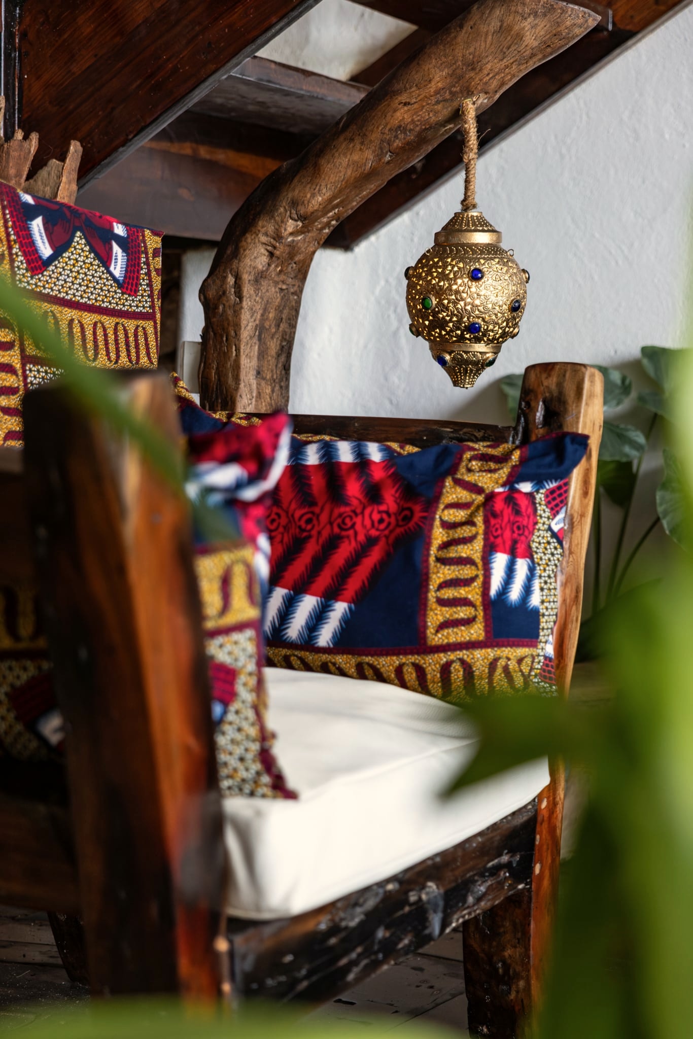 The Asili lounge: printed cushions on a low daybed, a pierced brass lantern, white walls