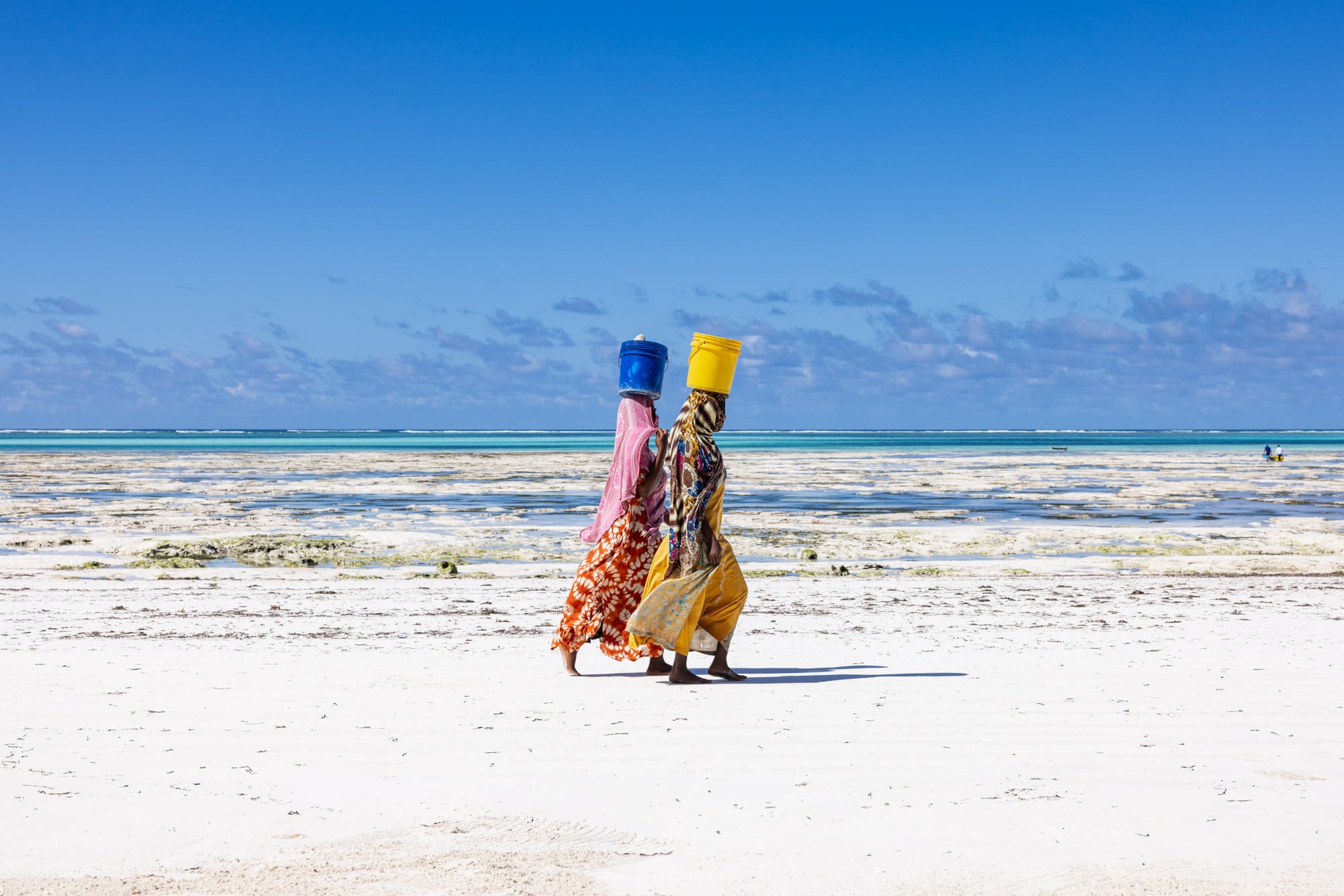 Two women walking the beach past Matlai with their octopus catch in buckets carried on their heads.