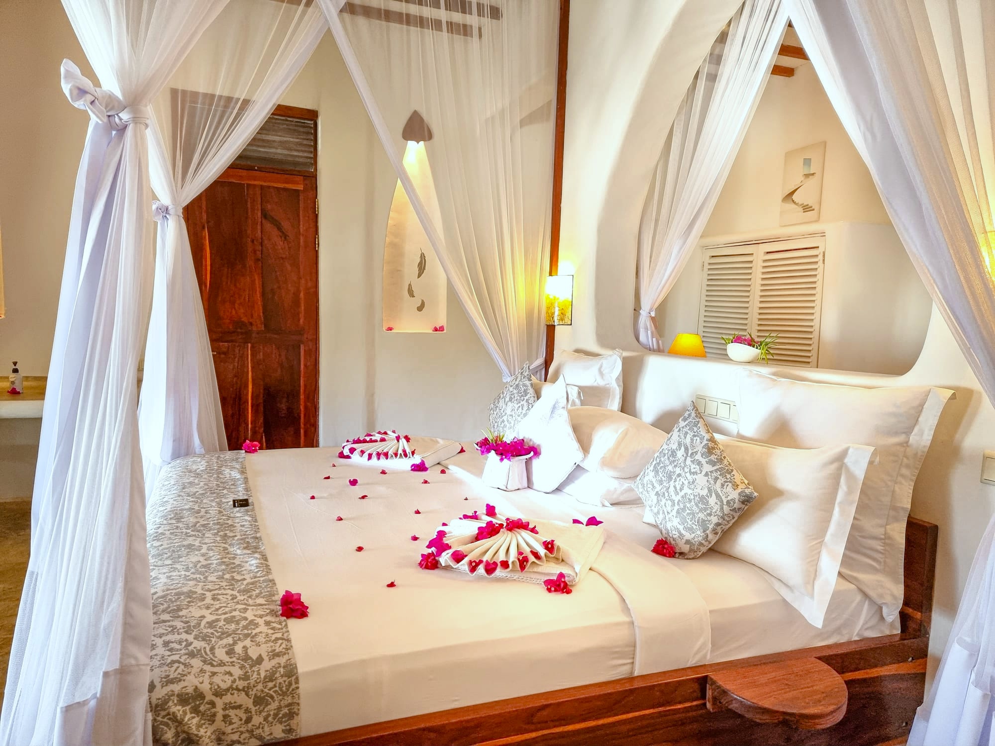 The Hewa room at Asili House, a four-poster bed under a mosquito net beside doors to the balcony