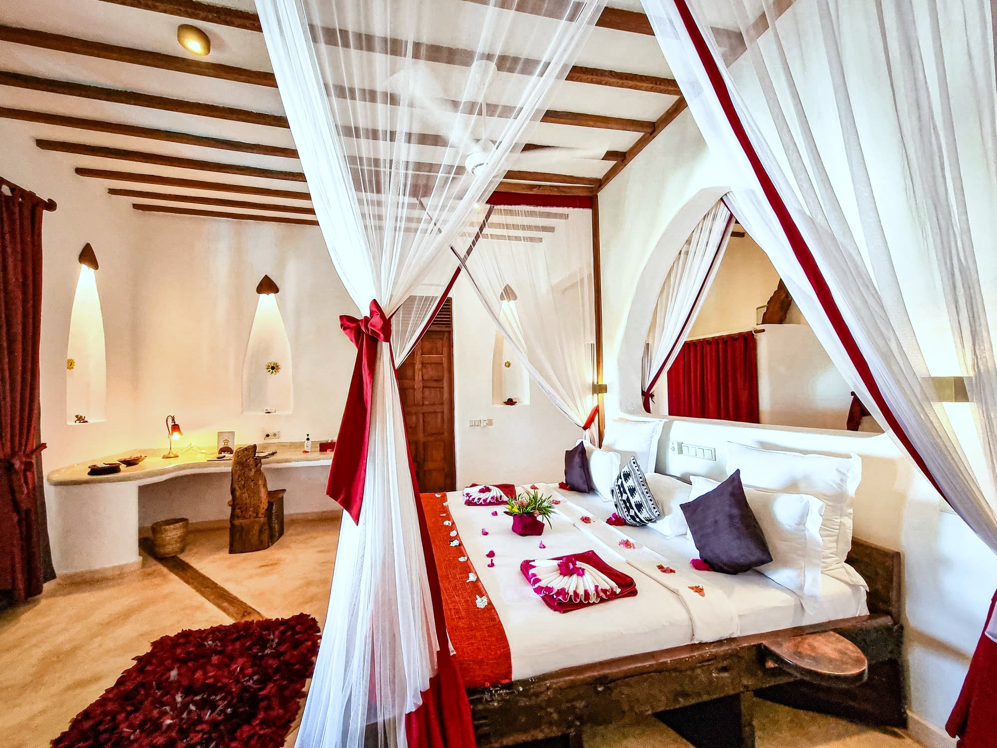 The Moto room at Asili House, a four-poster bed under a mosquito net with crimson textiles