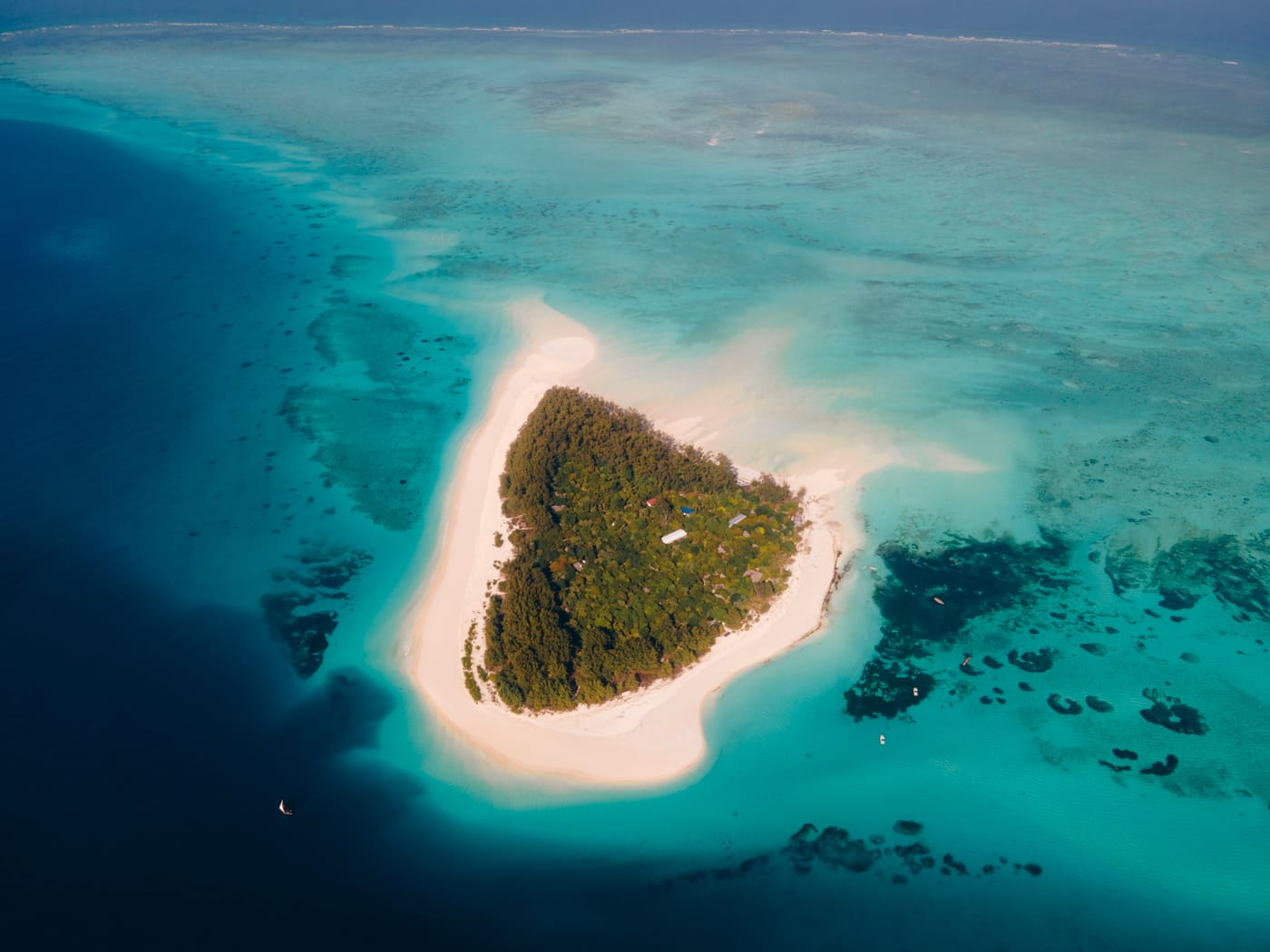 Aerial view of a tropical island sandbank in Zanzibar showing the turquoise Indian Ocean and coral reef lagoon on the east coast of Zanzibar