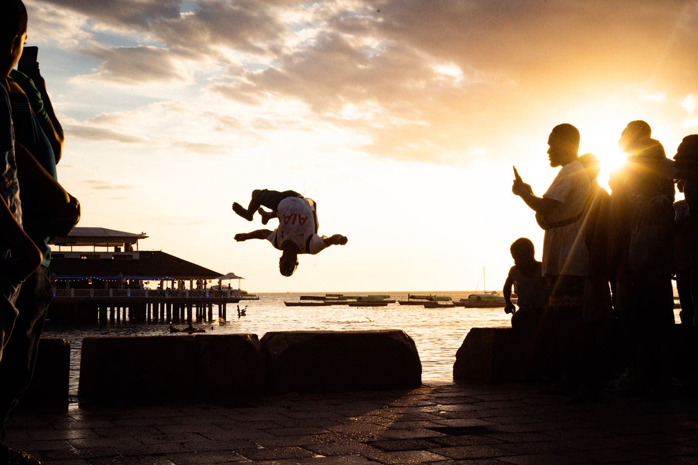 stone town pier sunset zanzibar locals jumping ocean