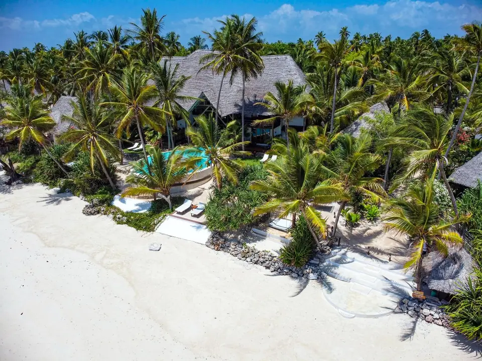 Drohnenaufnahme des Asili House, verborgen zwischen Kokospalmen, mit dem Strand von Michamvi Pingwe im Boutique Hotel Matlai Sansibar.