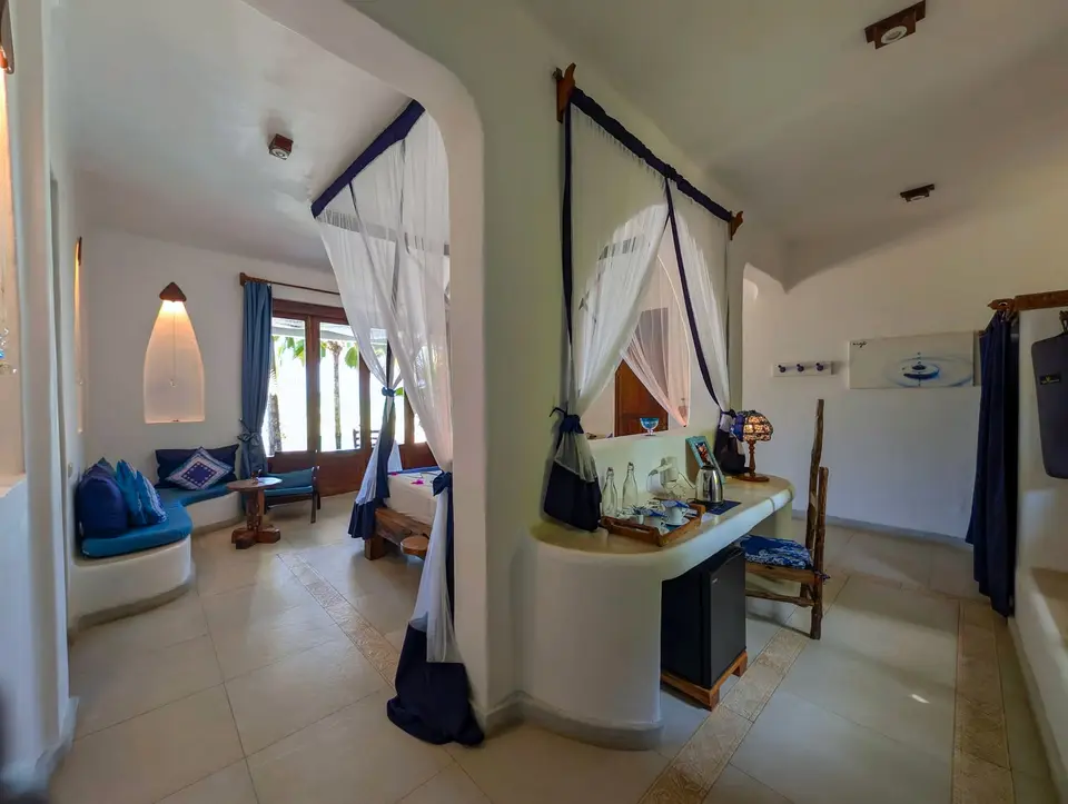Innenansicht von Zimmer Maji im Asili House, Boutique Hotel Matlai Sansibar, mit Kleiderschrank, Safe, Kaffeestation, Yogamatten und Platz für ein Zustellbett.
