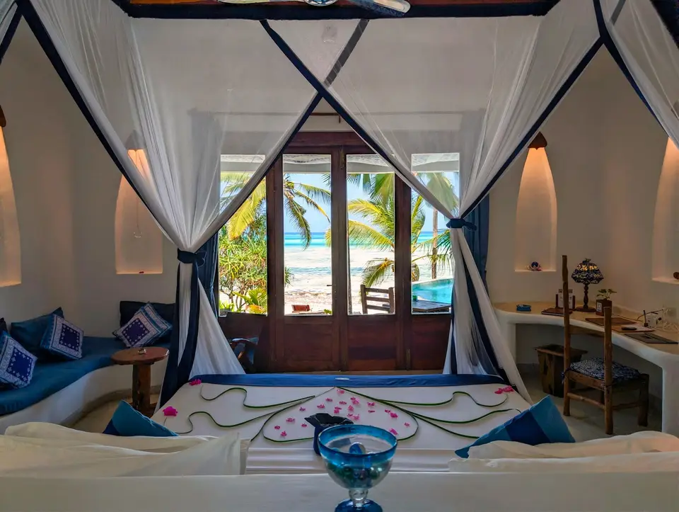 Blick vom Bett in Zimmer Maji im Asili House, Boutique Hotel Matlai Sansibar, mit Balkon, Pool und Meer.