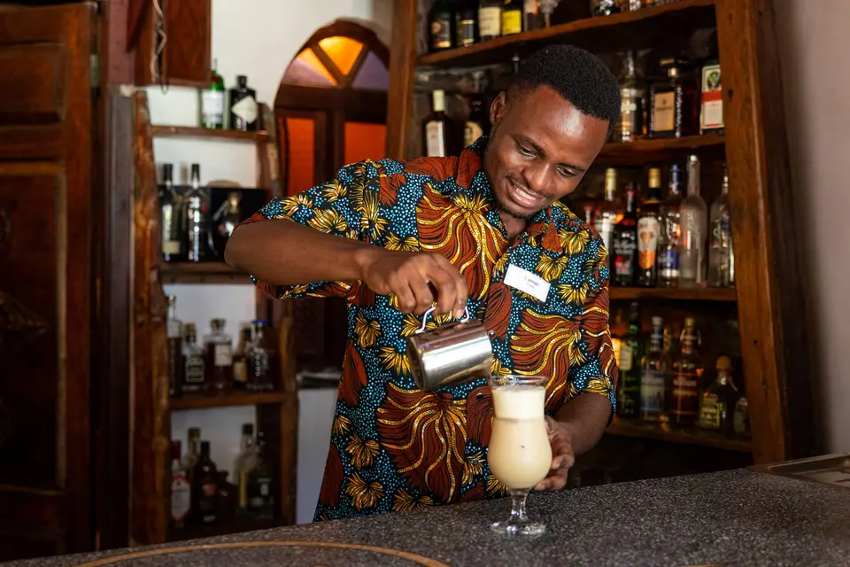 Barkeeper bereitet mit Freude einen Cocktail in der Zatiny Bar, Boutique Hotel Matlai Sansibar, zu.