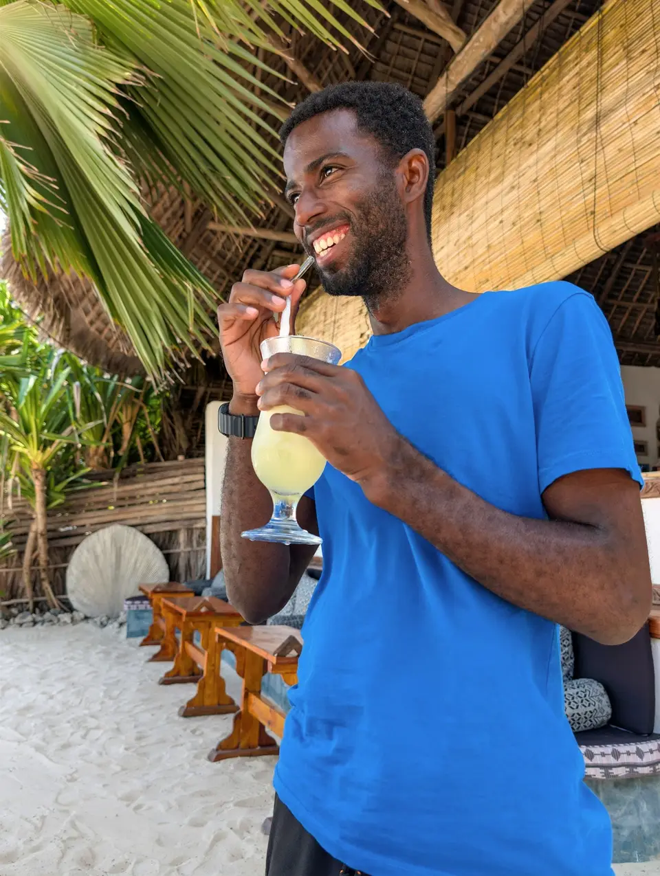 Lächelnder Gast genießt einen Saft mit Blick auf das Meer im Boutique Hotel Matlai Sansibar.