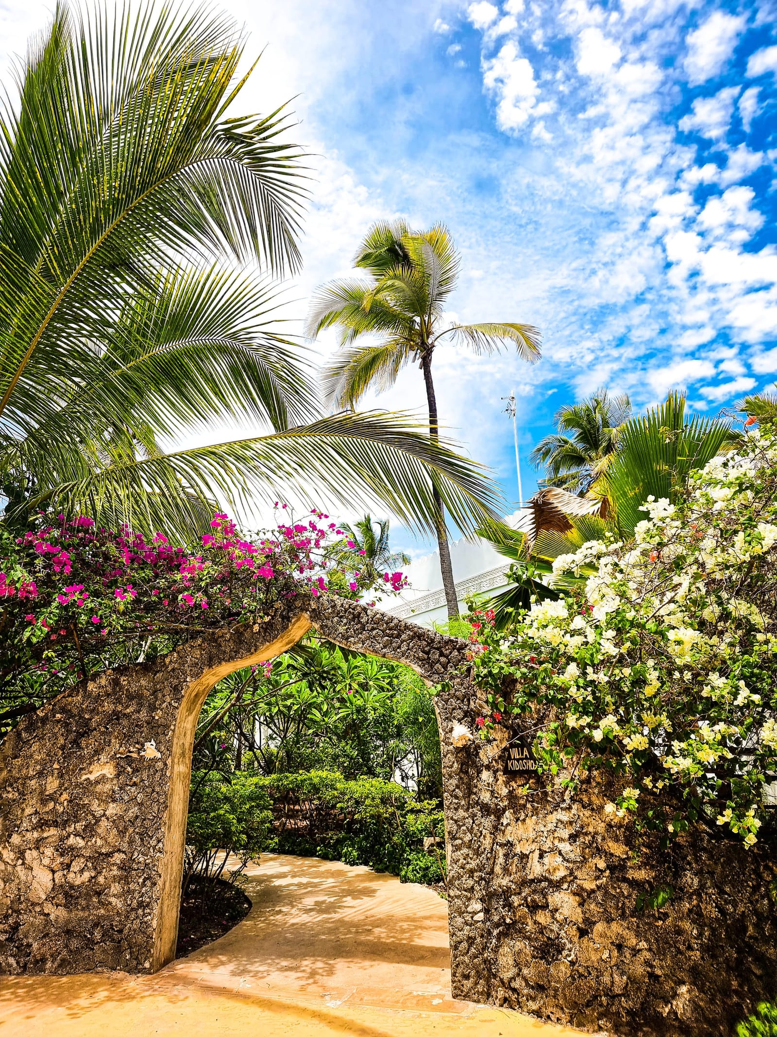 The coral-stone arch into Villa Kidosho, under bougainvillea.