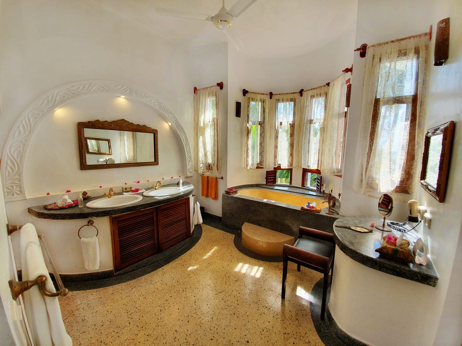The Jua bathroom at Villa Kidosho — a concrete bathtub set into a bay of shuttered windows, twin basins beneath a carved arch