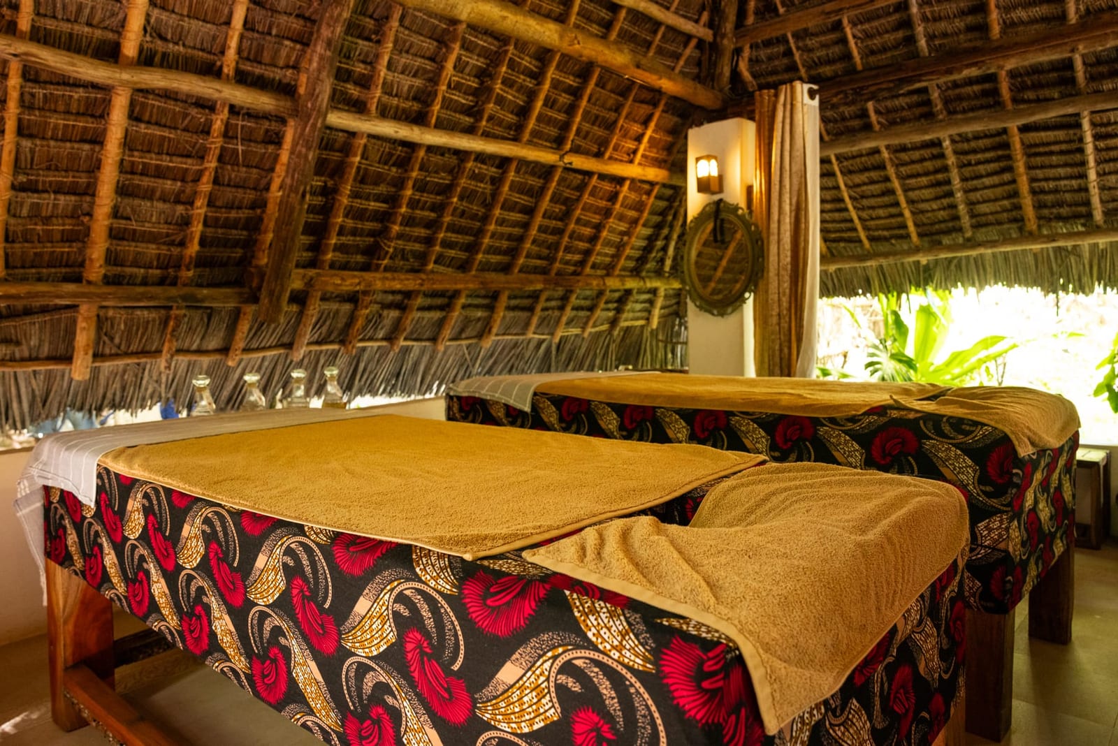 Two massage beds side by side at Bustani, made up with printed cloth and folded towels.