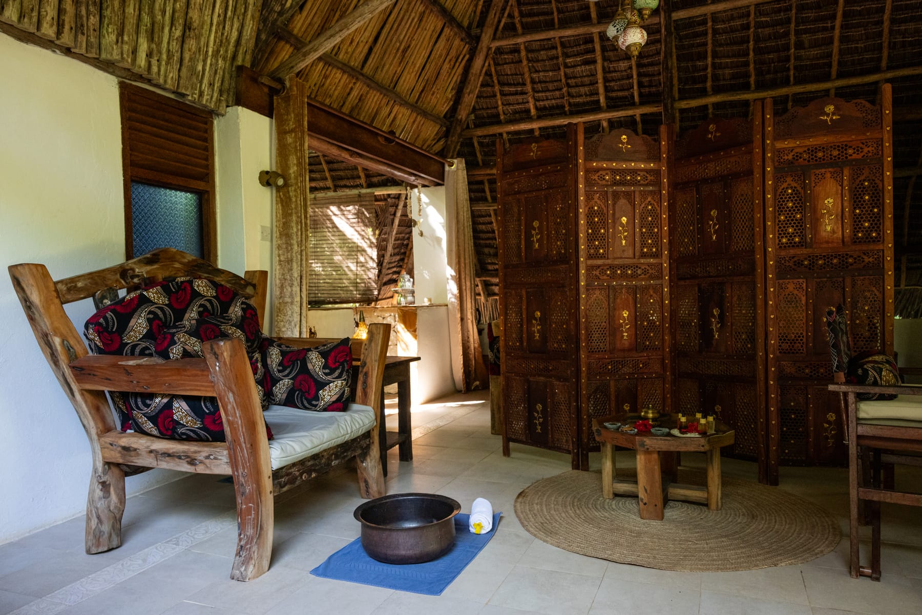 The treatment room at Bustani: wooden furniture, a carved screen, and the oils.